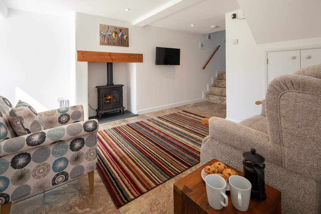 The cosy sitting-room is equipped with an electric wood-burner, perfect for those cosy nights in. The steps lead up to the bathroom.