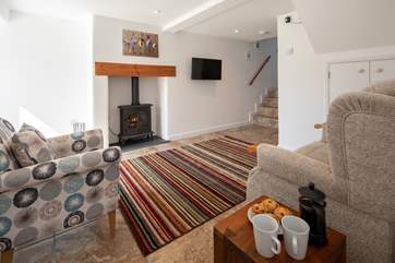 The cosy sitting-room is equipped with an electric wood-burner, perfect for those cosy nights in. The steps lead up to the bathroom.