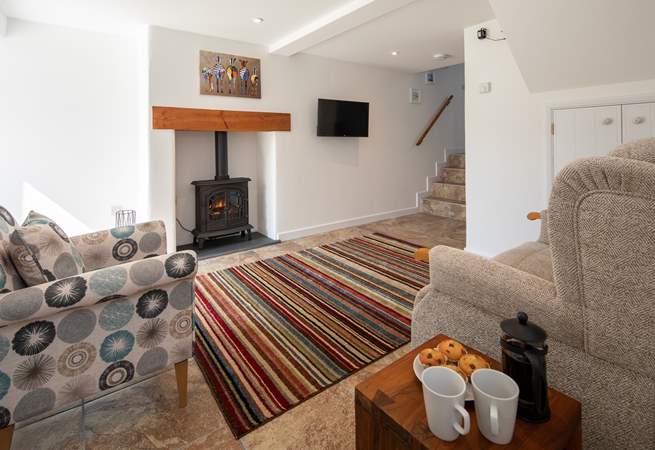The cosy sitting-room is equipped with an electric wood-burner, perfect for those cosy nights in. The steps lead up to the bathroom.
