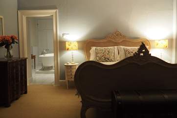 One of the beautiful en suite bedrooms with roll top bath and elegant antique French double bed.