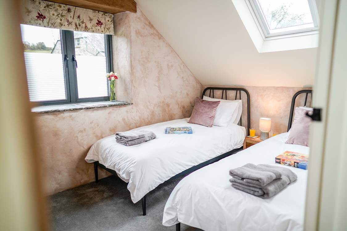 The light twin room has a wall-mounted TV. You will see the bottom half of the window is obscured for privacy, as this room looks out towards the owners' farmhouse.