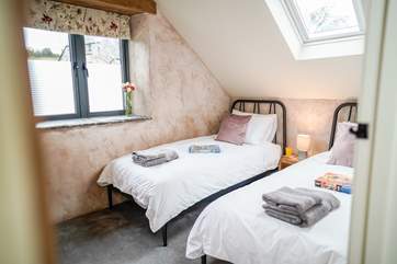 The light twin room has a wall-mounted TV. You will see the bottom half of the window is obscured for privacy, as this room looks out towards the owners' farmhouse.