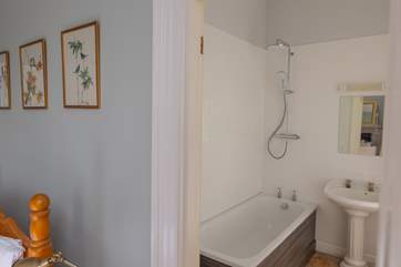 The en suite bathroom in bedroom 1, fitted with a waterfall shower and shower attachment over the bath.