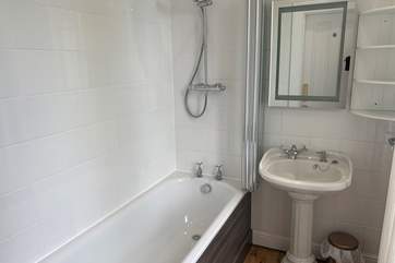 The en suite bathroom in bedroom 1, fitted with a waterfall shower over the bath.
