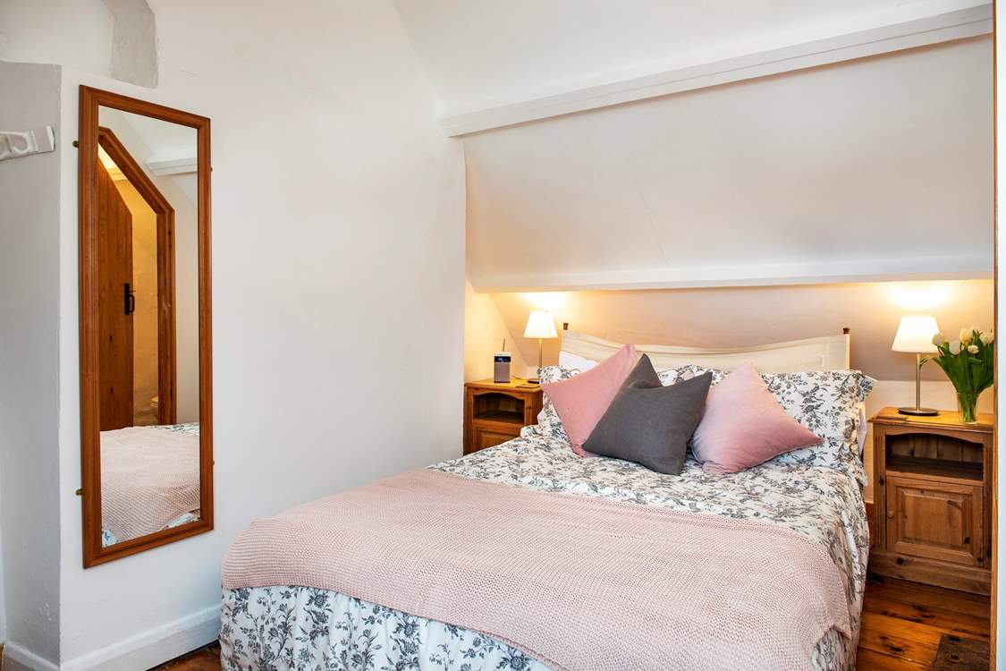 The bed in the second bedroom is adorned with lovely linens, cushions and throw.