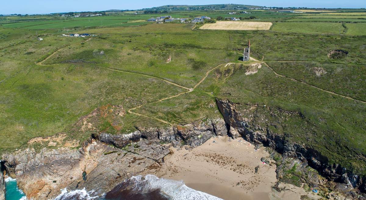 A view of Rinsey beach with the old Cornish engine house on the hill and the cottage in the middle to the left.