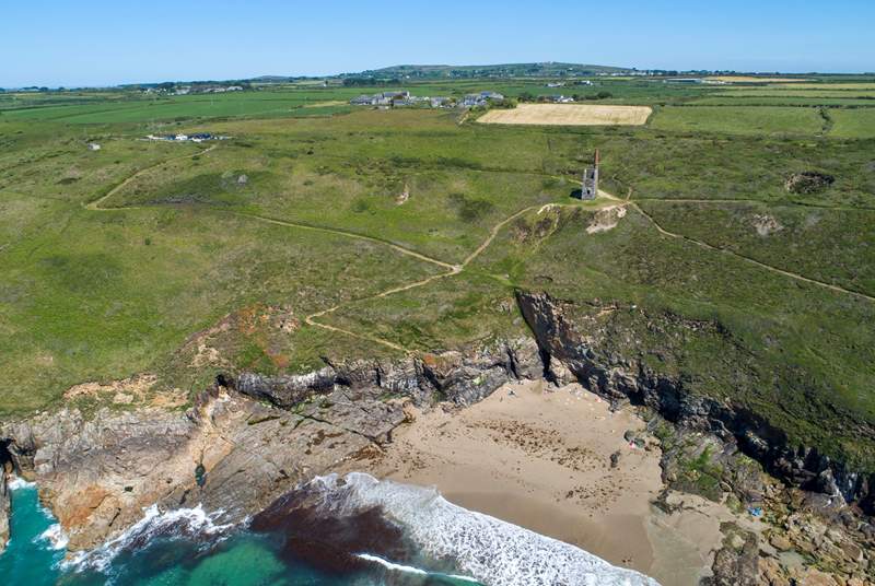 A view of Rinsey beach with the old Cornish engine house on the hill and the cottage in the middle to the left.