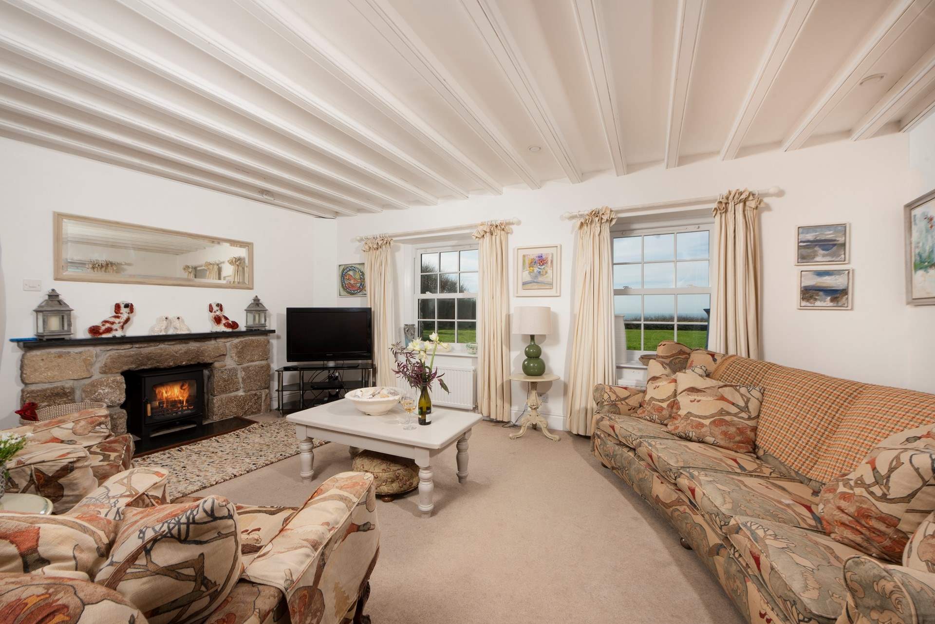 The sitting-room has beautiful beams, sea views and a wood-burner.