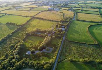 An ariel view of the lake and woods with the village of Woolsery in the distance. Straw Cottage is to the left of the white house in the centre of the photograph (the owners' home) and has its own large garden.