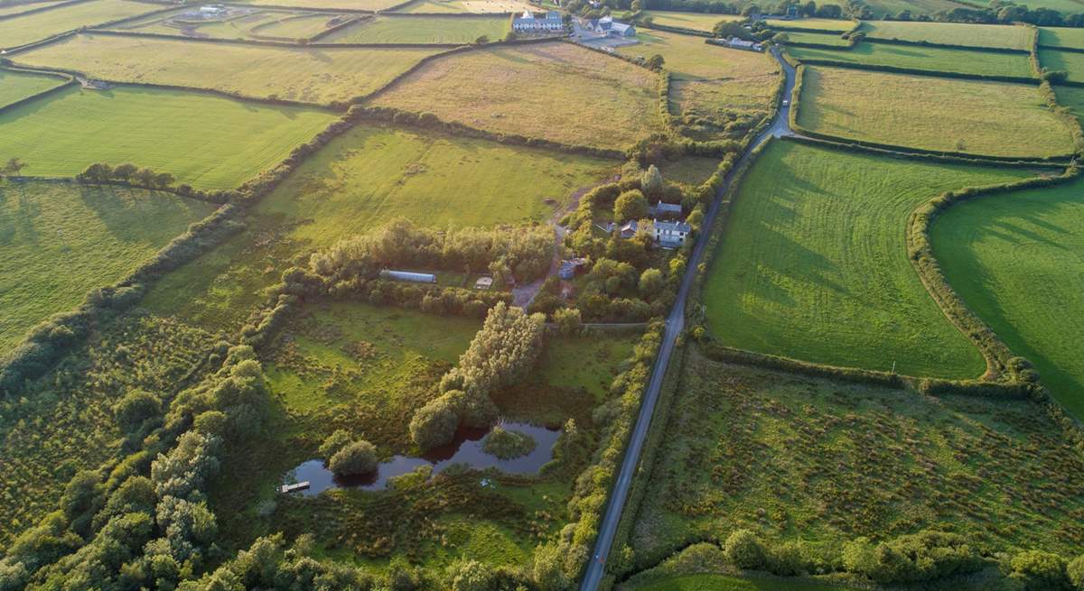 An ariel view of the lake and woods with the village of Woolsery in the distance. Straw Cottage is to the left of the white house in the centre of the photograph (the owners' home) and has its own large garden.