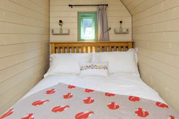 The comfortable double bed looks out to the double doors to the view beyond.