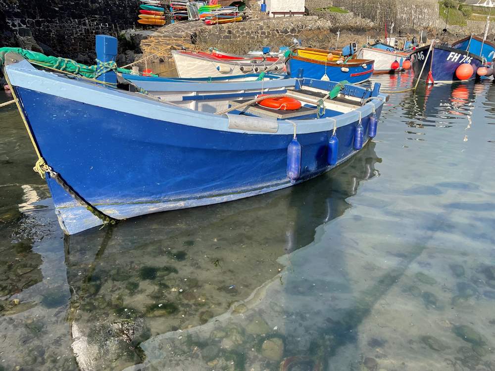 Pretty fishing boats rest in the harbour in Coverack.