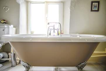 A bath with a view of rolling hills and the coast.