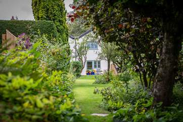 Gamekeeper's Cottage peeking through the lush green gardens.