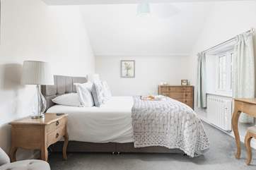 The beautiful main bedroom has pretty garden views.