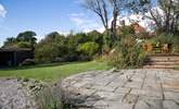 The patio with steps leading up to the decking where you can sit by the pond and admire the view. - Thumbnail Image