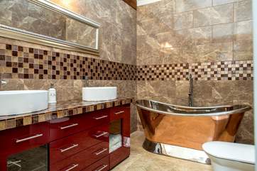 A little bit of luxury in the bathroom with twin sinks and a tin and copper bath.