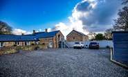 The Dairy has one designated parking space (white car) to the right of the stairs with additional parking to the back of the barn.