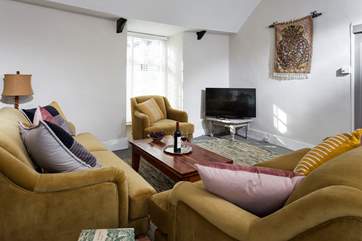 The large sitting-area has a vaulted ceiling. squishy velvet sofas and armchair, white wooden blinds and Smart TV.