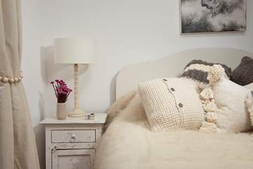 Fluffy throws and lovely cushions adorn the bed.