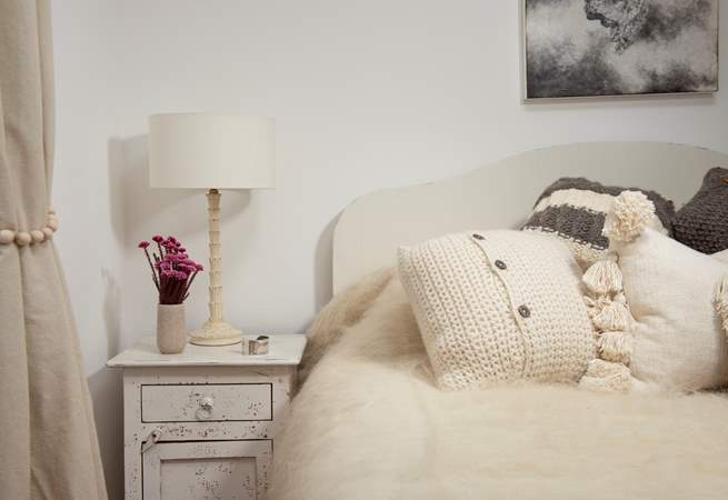 Fluffy throws and lovely cushions adorn the bed.