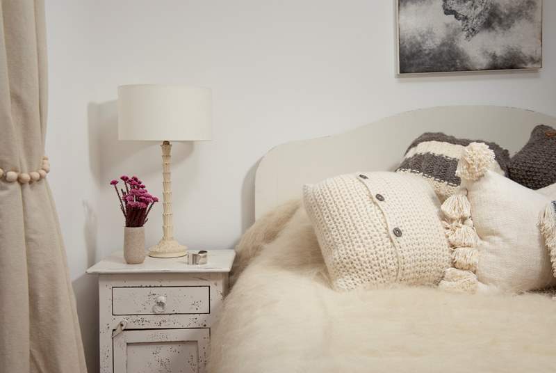 Fluffy throws and lovely cushions adorn the bed.