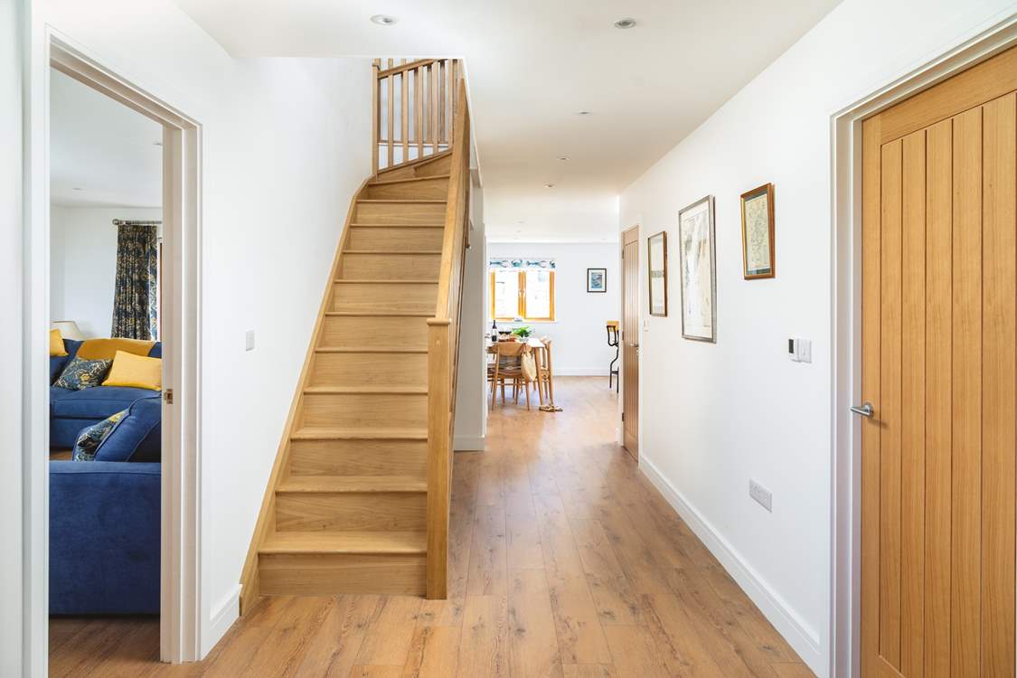 The front door opens to the coast path and inside you can see the open plan living space and sitting-room along with the oak staircase leading to the bedrooms.