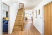The front door opens to the coast path and inside you can see the open plan living space and sitting-room along with the oak staircase leading to the bedrooms.