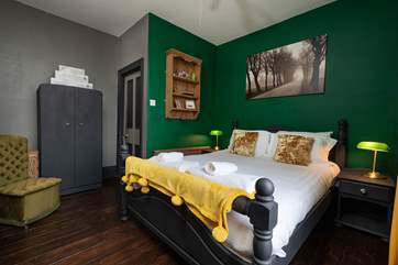 The dark walls and furniture complement the original wood flooring in this handsome bedroom.