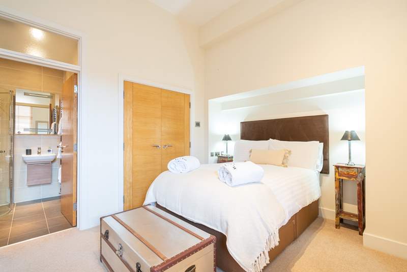 The spacious main bedroom on the ground floor with comfy bed and crisp white linens, perfect to sink into after a day out exploring.