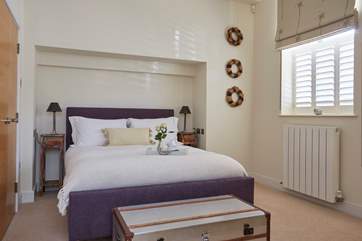 The spacious main bedroom on the ground floor with comfy bed and crisp white linens, perfect to sink into after a day out exploring.