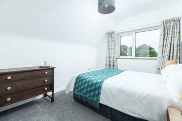 Bedroom 4 has a double bed, luxurious bedding and a garden view.