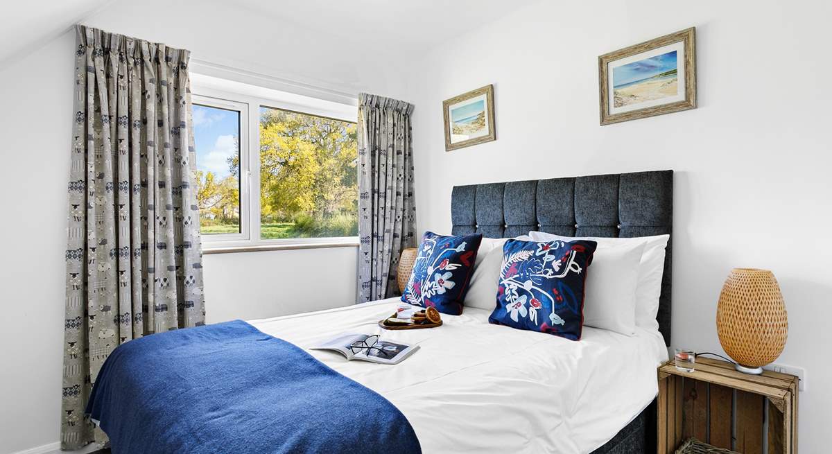 Bedroom 4 has a double bed, luxurious bedding and a garden view.