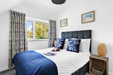 Bedroom 4 has a double bed, luxurious bedding and a garden view.