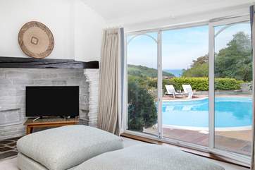 The sitting-room is steeped in luxury, large windows overlook the pool, garden and sea beyond.
