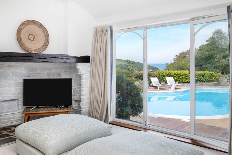 The sitting-room is steeped in luxury, large windows overlook the pool, garden and sea beyond.  