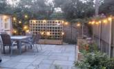 The patio at dusk - pretty lights and colourful flower beds.  - Thumbnail Image