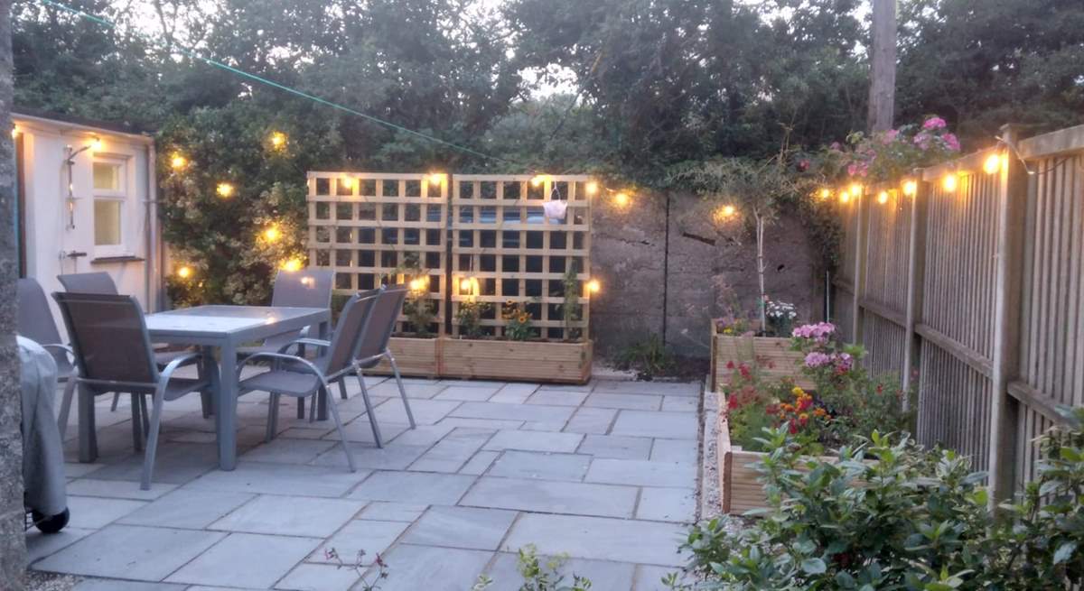 The patio at dusk - pretty lights and colourful flower beds. 