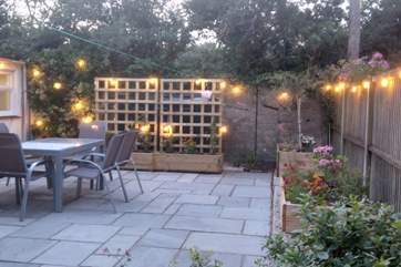 The patio at dusk - pretty lights and colourful flower beds.