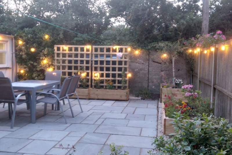 The patio at dusk - pretty lights and colourful flower beds. 