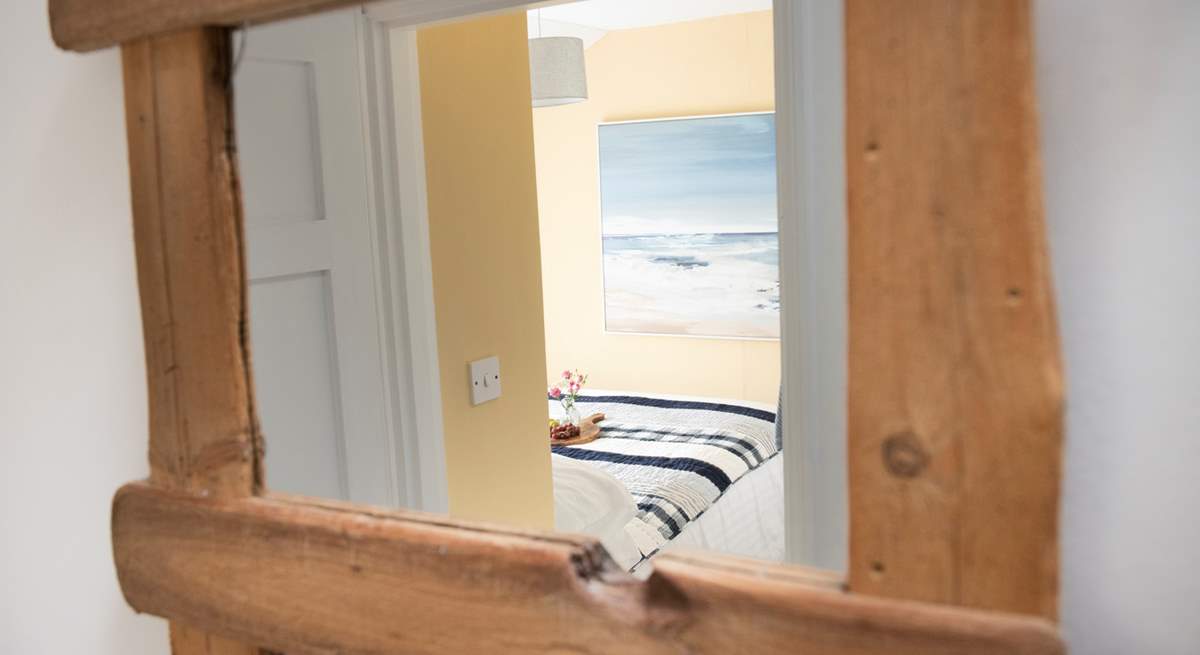 The reclaimed wooden mirror frames the bedroom perfectly.