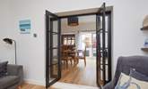 View through the open doors to the welcoming dining room, kitchen and outdoor patio area. - Thumbnail Image