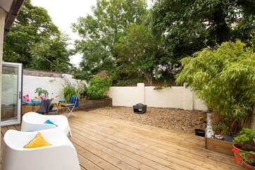Surrounded by wooden planters and trees, step outside into the secluded back garden and relax around the fabulous fire-pit.