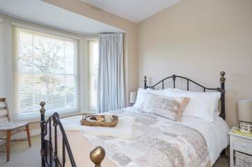 The pretty main bedroom is furnished with an ornate, comfy double bed.