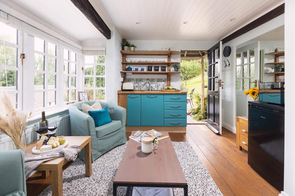 To the right, you can see the fridge and microwave. The kettle and coffee machine are also positioned here. The plug-in double hob is tucked away in the kitchen cupboards.