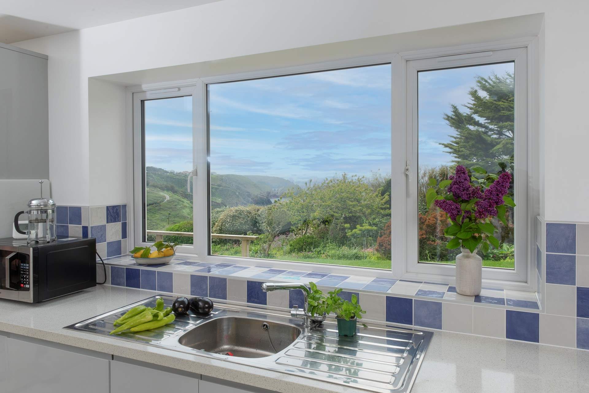 The kitchen overlooks the mature garden, which is abundant in plants, shrubs and foliage.