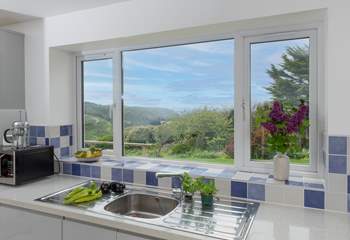 The kitchen overlooks the mature garden, which is abundant in plants, shrubs and foliage.