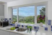 The kitchen overlooks the mature garden, which is abundant in plants, shrubs and foliage.