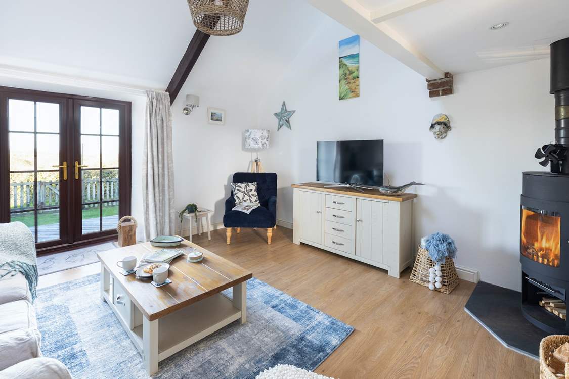 The lovely sitting-room has a wood-burner for cooler months and access to the decked area and garden for sunny days.