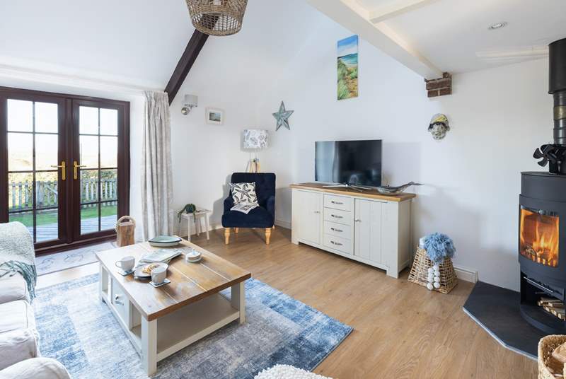 The lovely sitting-room has a wood-burner for cooler months and access to the decked area and garden for sunny days.
